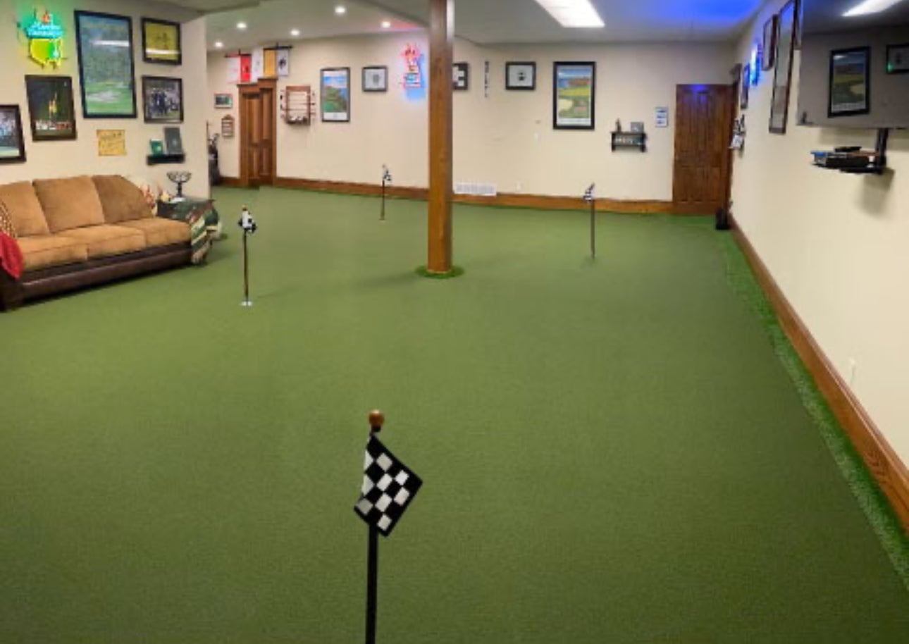 Indoor putting green with flags and a couch in the background