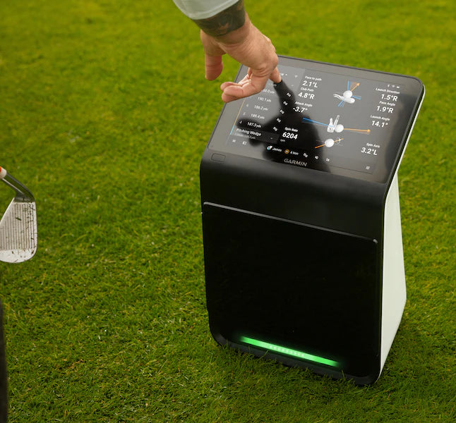 Golf analytics device on grass with a hand interacting with the screen Garmin Approach R50