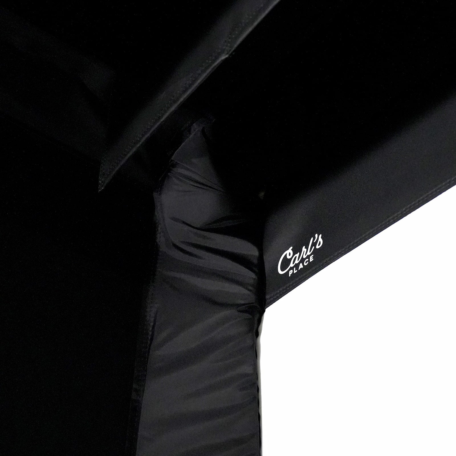 Black umbrella with 'Carl's Place' branding on a white background