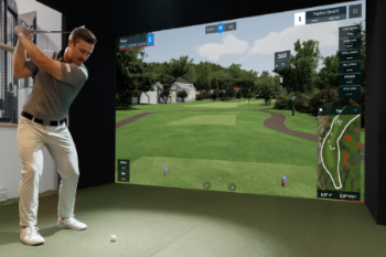 Man playing golf simulation game on a large screen indoors